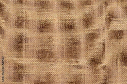 Brown burlap cloth background or sack cloth for packing. Natural linen threads texture. Sackcloth, empty space. Wrapping detail, old grainy cotton backdrop close-up.
