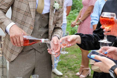 The groom pours a glass of champagne to the wedding guests.