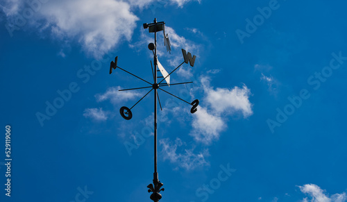 wind rose and weather vane on the blue sky with clouds