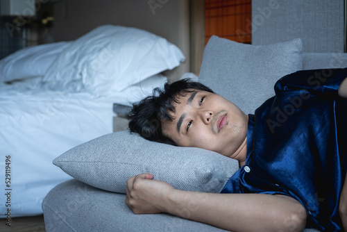 man sleeping on the sofa with empty bed behind him