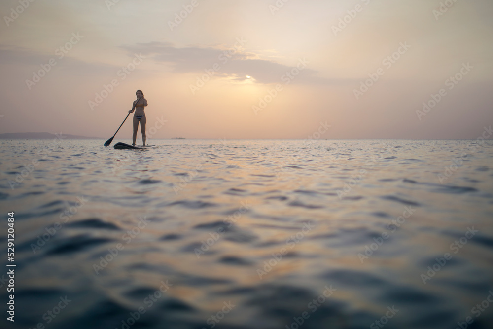 Woman paddleboarding on sea, copy space
