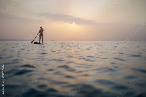 Woman paddleboarding on sea, copy space © yossarian6