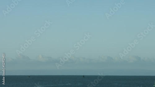 Timelapse of Two Fishing Boats Heading Out to Sea at Sunrise from Swansea UK with Devon Coastline in Distance 4K photo