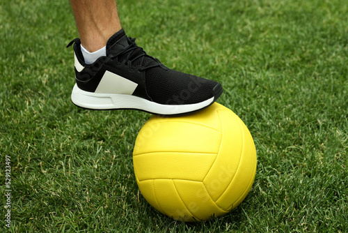 Male legs in sneakers and volleyball ball on grass