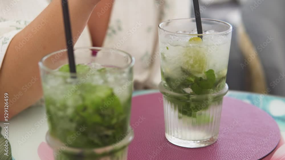 Close up shot of a hand swirling frozen cubes in a glass of water with mint Close up shot of a hand swirling frozen cubes in a glass of water with mint