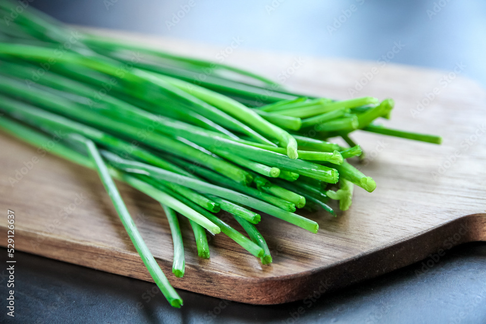 Bunch of chives on a wooden cutting board - obrazy, fototapety, plakaty 