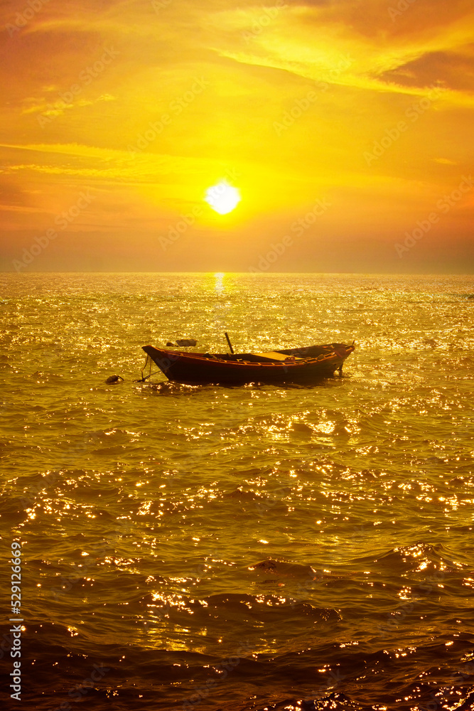 A small fishing boat in the middle of the sea at sunset