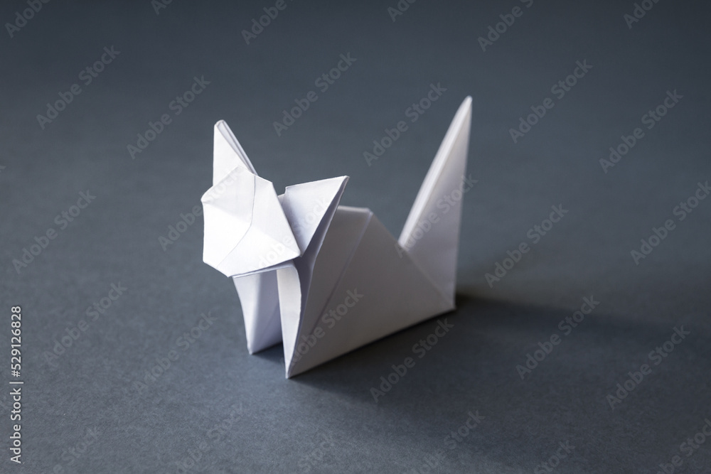 White paper cat origami isolated on a grey background White paper cat origami isolated on a grey background