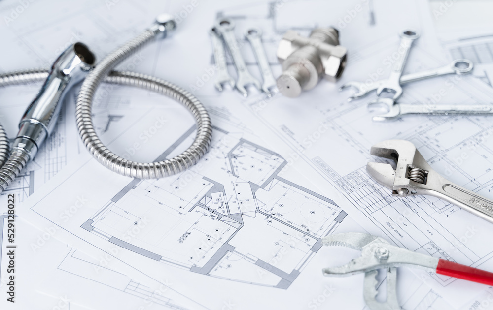Plumbing project in house.Drawing,diagrams,plan of water supply of apartment,building.Man repairer making repairs at home.Devices,accessories, hose,tap,adjustable wrench,pressure reducer,tape measure Plumbing project in house.Drawing,diagrams,plan of water supply of apartment,building.Man repairer making repairs at home.Devices,accessories, hose,tap,adjustable wrench,pressure reducer,tape measure