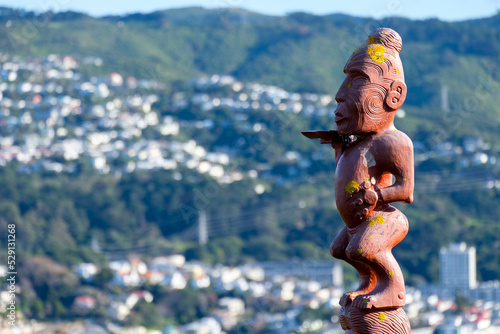 Māori pou intricate carved cultural monument sculpture on popular tourism landmark Mt Vic with residential houses in Capital Wellington, New Zealand Aotearoa, close up photo