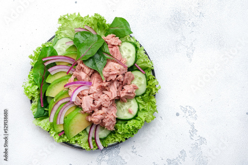 Tuna fish salad with avocado, cucumber, red onion and lettuce. White stone background, top view, copy space
