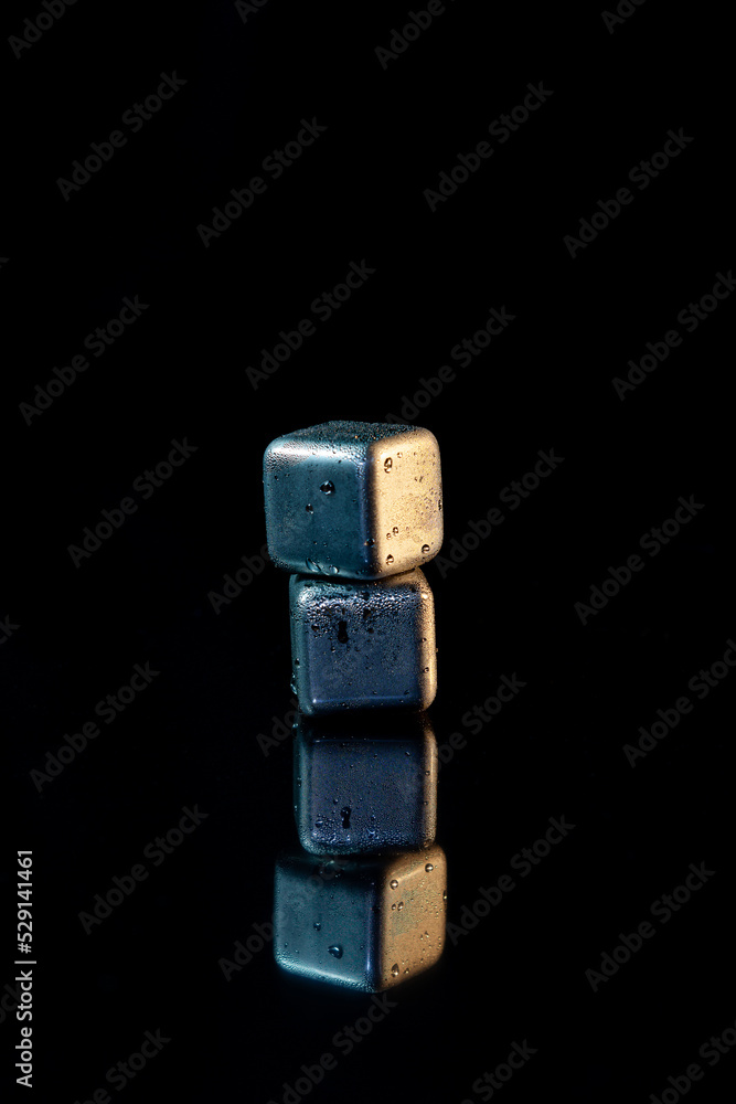 Stainless steel cubes simulating ice for cooling drinks on a black surface with a reflection. Stainless steel cubes simulating ice for cooling drinks on a black surface with a reflection.