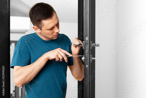 a man repairing a door knob. locksmith fixing a wooden door.