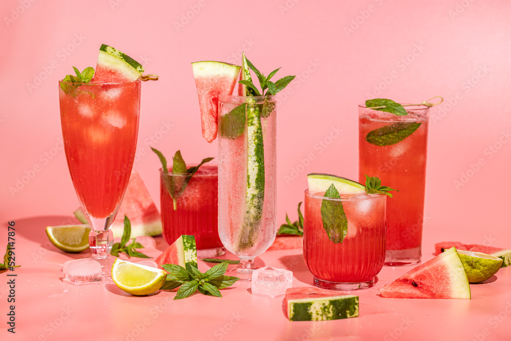 Different elegant glasses with watermelon cocktail. Splash, splatter, water drops on the pink background with sun light Different elegant glasses with watermelon cocktail. Splash, splatter, water drops on the pink background with sun light