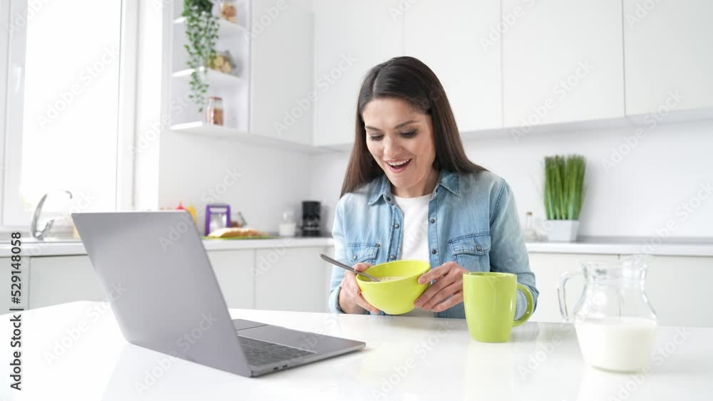 Positive lady have web meeting netbook speak family eat granola in kitchen Positive lady have web meeting netbook speak family eat granola in kitchen