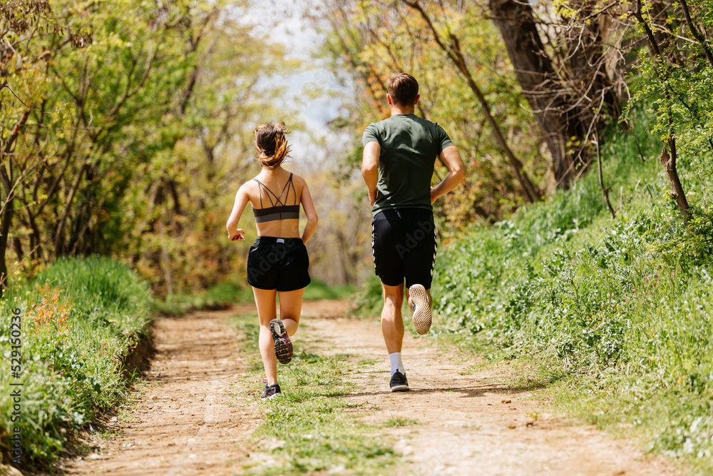 Sport people running in park together. Young couple jogging at outdoor workout. Fitness woman and man running marathon at sunset in park Sport people running in park together. Young couple jogging at outdoor workout. Fitness woman and man running marathon at sunset in park