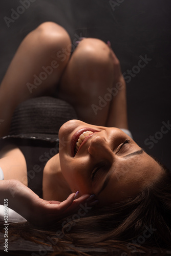 A portrait of a beautiful woman wearing a black bodysuit lying on the floor. fashion, style, beauty