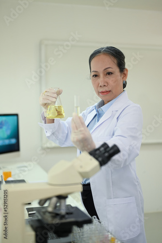Professional senior female researcher preparing and analyzing microscope slides, conducting research investigations in laboratory