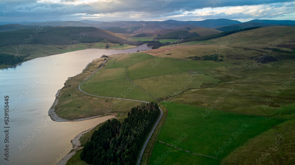 Naklejka premium aerial picture of grassy meadows and a water reservoir at twilight