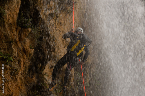 Obraz na plátne Unrecognizable person with climbing equipment and helmet descending with the hel