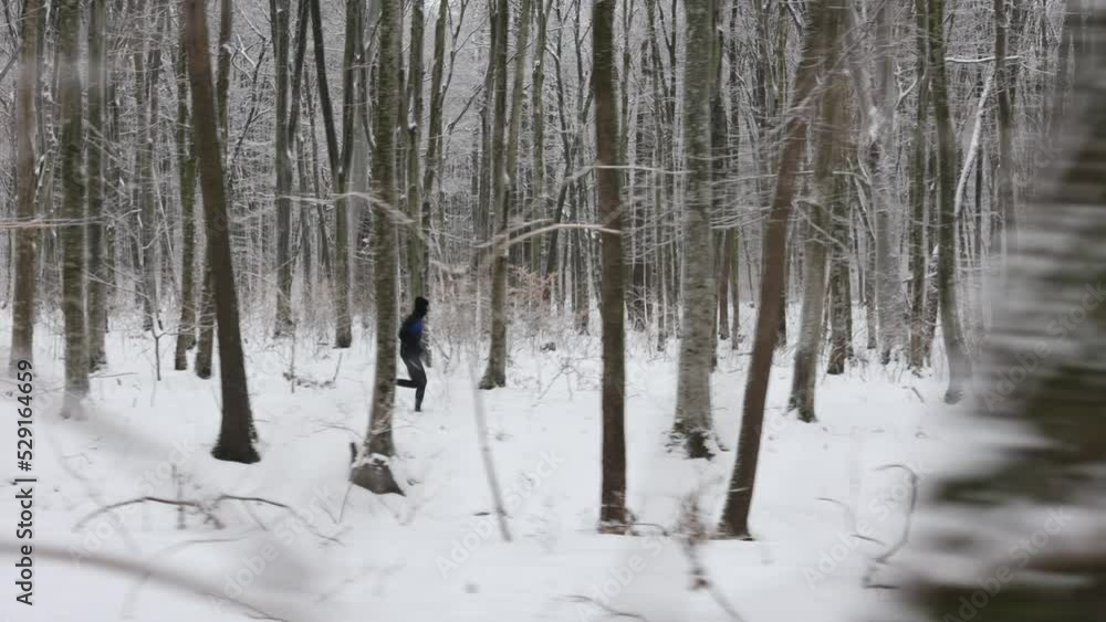 Active young guy dressed in black sport clothes spending morning time for jogging outdoors. Caucasian sporty man enjoying leisure activity among forest with snow lying around. Active young guy dressed in black sport clothes spending morning time for jogging outdoors. Caucasian sporty man enjoying leisure activity among forest with snow lying around.