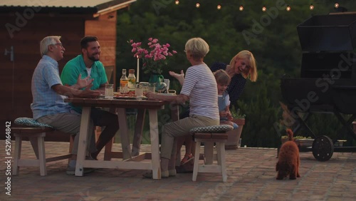 Cheerful family enjoying a family dinner outside at home during evening
