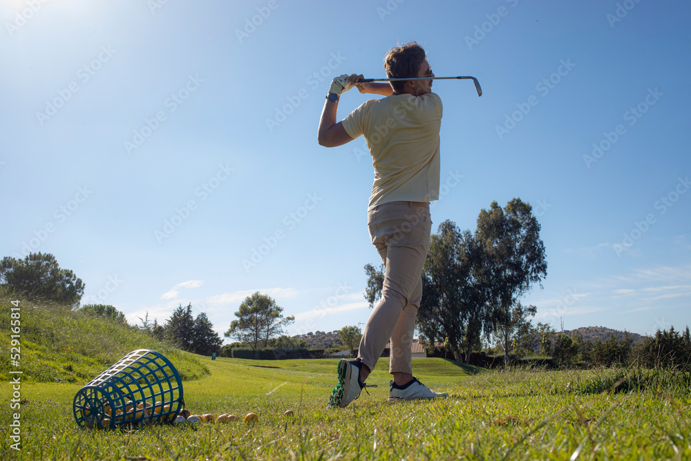 golfer practicing hitting golf balls. golf training on the driving range. golfer  practicing swing. basket with practice golf balls. healthy sports golf. golfer  practicing golf swing on driving range Stock Photo