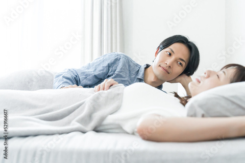 寝室で寝ている妻を見る夫