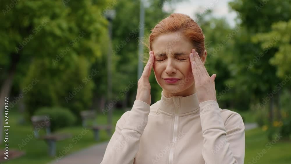 Young woman having severe migraine while running in the park. Female stops because of head pain. Potrait of suffering, health problems. Health concept. Jogging outdoor. Young woman having severe migraine while running in the park. Female stops because of head pain. Potrait of suffering, health problems. Health concept. Jogging outdoor.