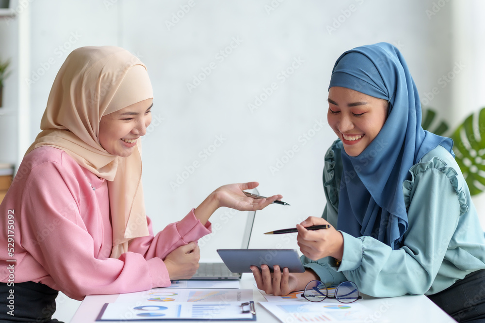 Two beautiful Muslim business woman wearing hijab talk and discuss accounting and finance. and cooperate with the marketing department Marketing and Investment Planning. Two beautiful Muslim business woman wearing hijab talk and discuss accounting and finance. and cooperate with the marketing department Marketing and Investment Planning.