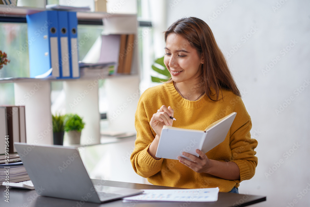 Beautiful young Asian business woman working on her laptop enjoy smiling and happy working, taking note, reviewing work and reading with peace of mind. Beautiful young Asian business woman working on her laptop enjoy smiling and happy working, taking note, reviewing work and reading with peace of mind.