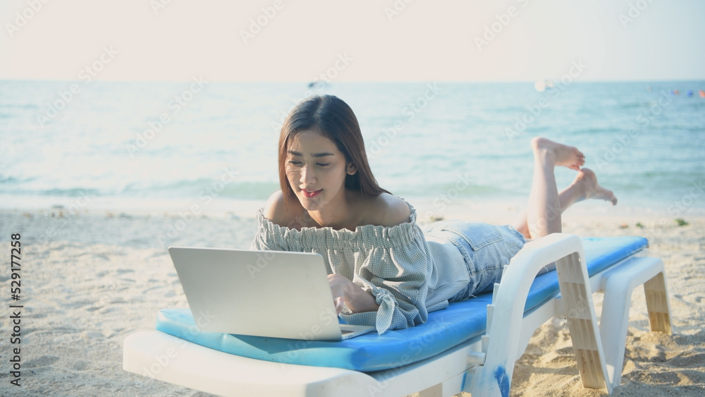 Holiday concept of 4k Resolution. Asian woman working using a laptop on the beach.