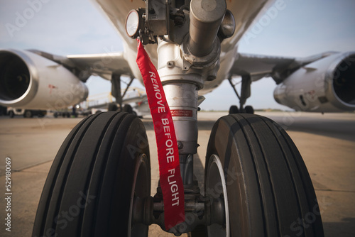 Aircraft nose wheel with red flag Remove Before Flight. Selective focus on airplane at airport..