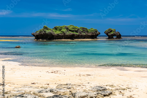 Crystal clear waters of the turquoise sea forming a natural pool, green coastal rocks, blue sky.