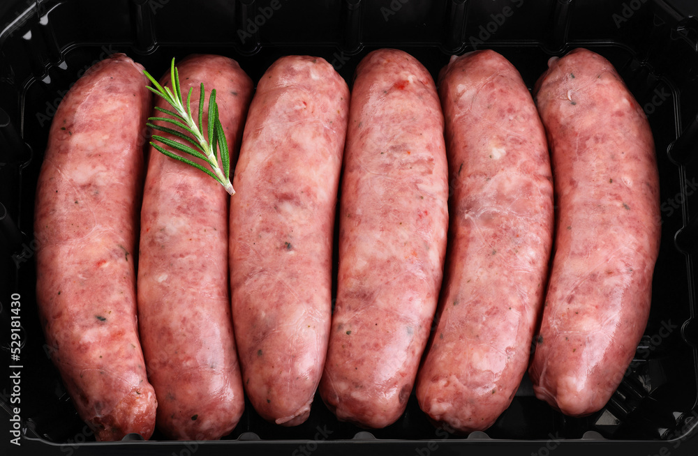 Raw German, Munich, Bavarian, sausages with rosemary in a black plastic container. Raw German, Munich, Bavarian, sausages with rosemary in a black plastic container.