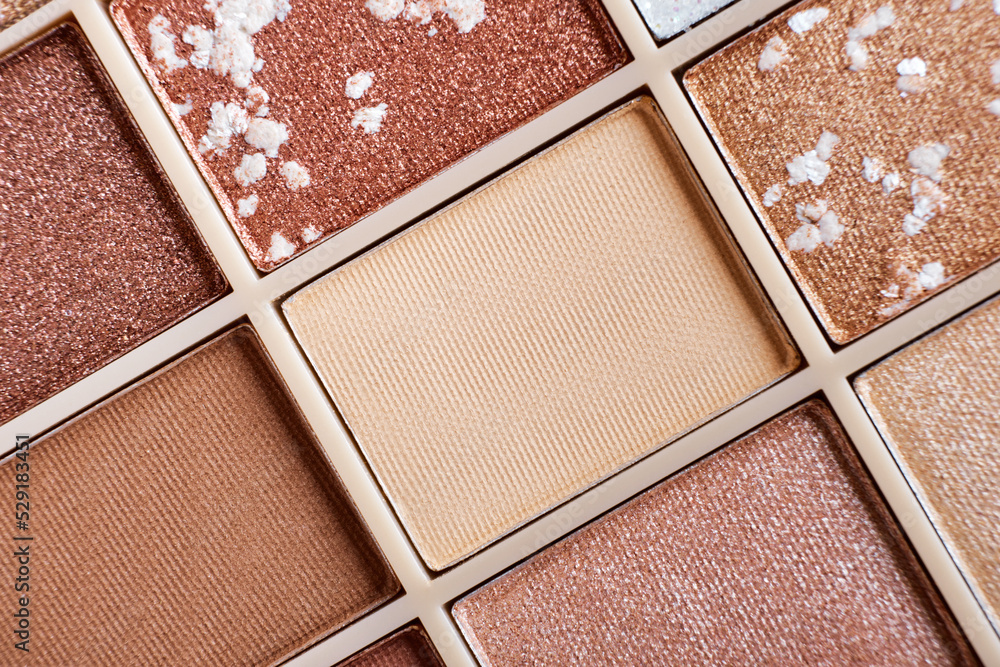 Fototapeta premium Eyeshadow colorful shades palette in beige tones close-up. Beauty abstract background