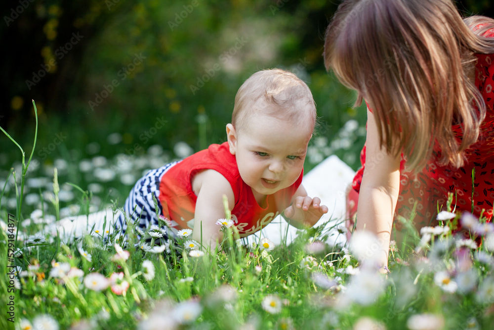 Brother and sister playing on grass in summer day. Two children are sitting on green meadow and smile in the par. Brother and sister playing on grass in summer day. Two children are sitting on green meadow and smile in the par.