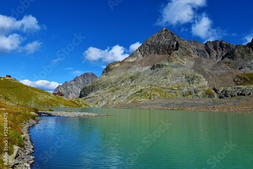 Shore of Großer Gradensee lake and Adolf Noßberger Hütte with the peak of Petzeck mountain in Gradental valley in Schober group sub-range of Hohe Tauern in Central Eastern Alps, Carinthia, Austria