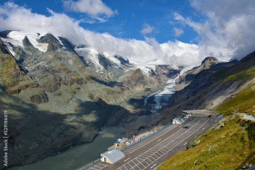 View of Pasterze Glacier in Glockner Group in High Tauern in Austrian Central Alps, Carinthia, Austria and a large car parking lot at the top of a parking garage