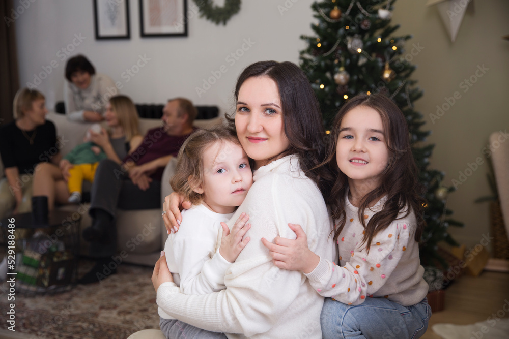 mom and two little daughters celebrate Christmas with family and friends at home. 
