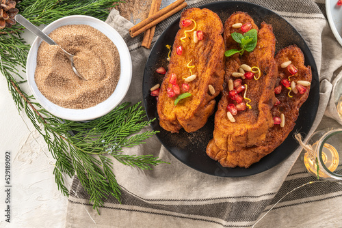 Foto Traditional Christmas Rabanadas with lemon zest, pomegranate, pine nuts and cinnamon