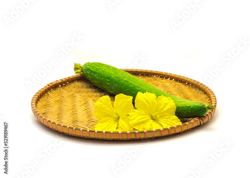 Homegrown blooming luffa flower with fresh cut fruit arrangement on handmade flat winnowing basket isolated on white background