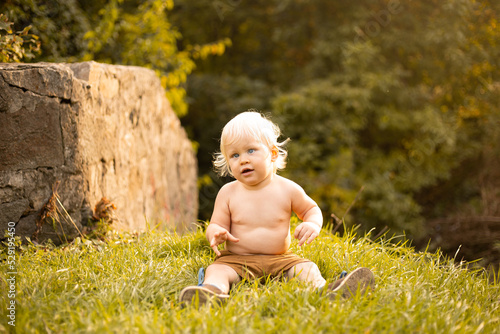 happy child wearing shorts in autumn or summer park with golden and green trees © Marharyta