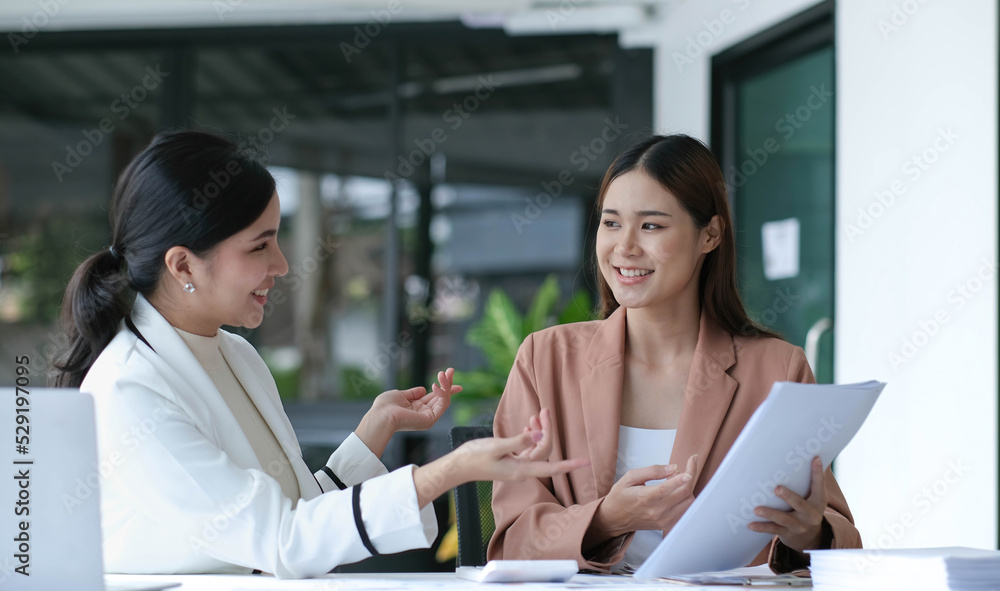 Two young beautiful asian business woman in the conversation, exchanging ideas at work. Two young beautiful asian business woman in the conversation, exchanging ideas at work.