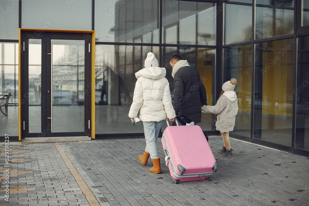Mother, father and daughter with luggage going to airport terminal - obrazy, fototapety, plakaty 