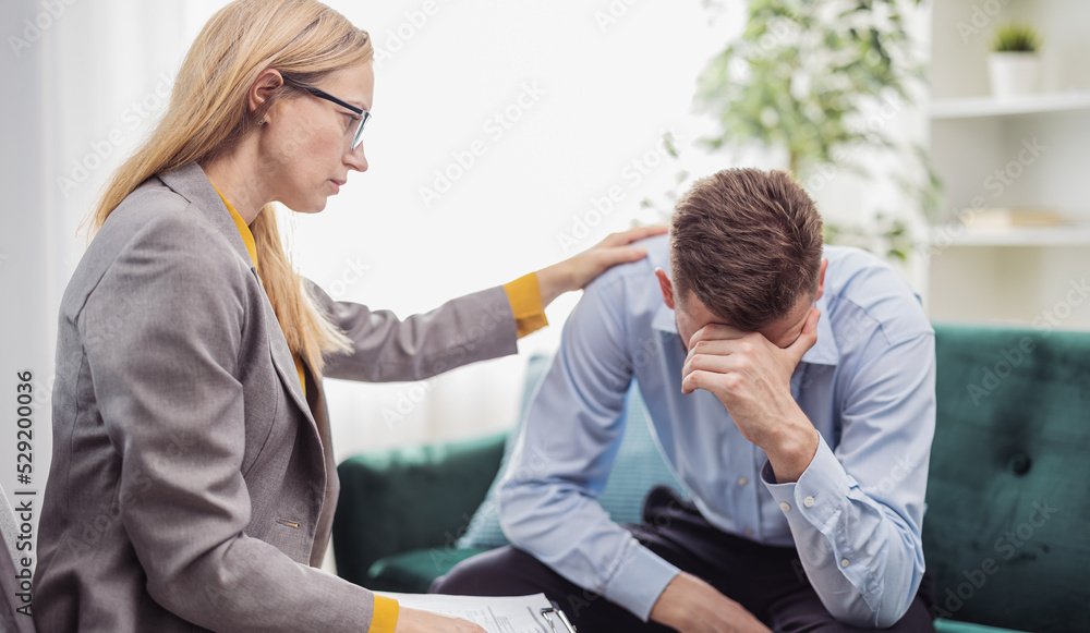 Fototapeta premium Mature blond woman psychologist helps stressed man, talk about motivation, health care concept