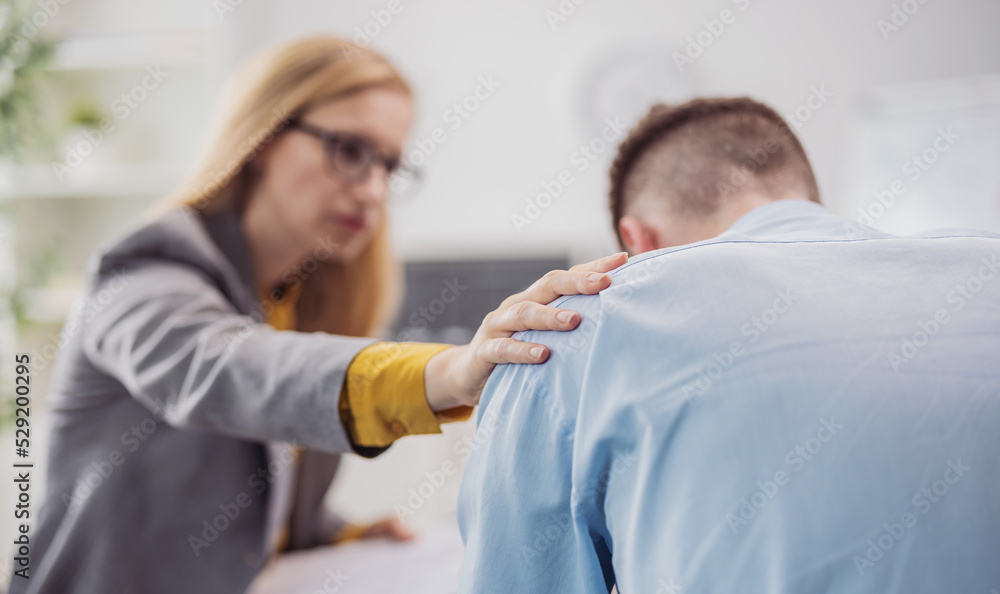 Obraz premium Defocused blond woman psychologist helps stressed patient man sitting in bright doctor office, health care concept