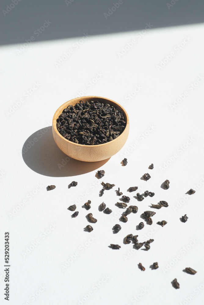 Chinese green tea in a wooden bowl. Dry leaves in container on white background. Organic high-quality ingredient for a drink Chinese green tea in a wooden bowl. Dry leaves in container on white background. Organic high-quality ingredient for a drink