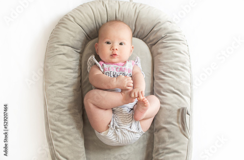 Fototapeta Cute caucasian newborn baby girl in the baby nest playing with her feet
