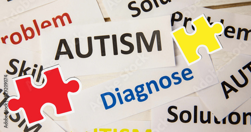 Image of red and yellow puzzle pieces falling over autism text on white background